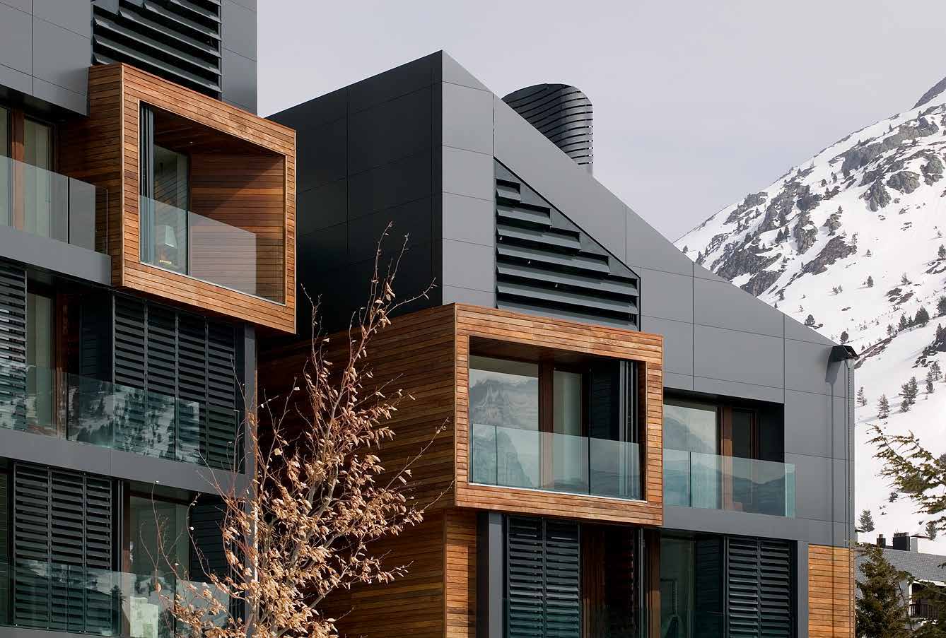 Edificio de fachadas oscuras y balcones enmarcados en madera, junto a la montaña